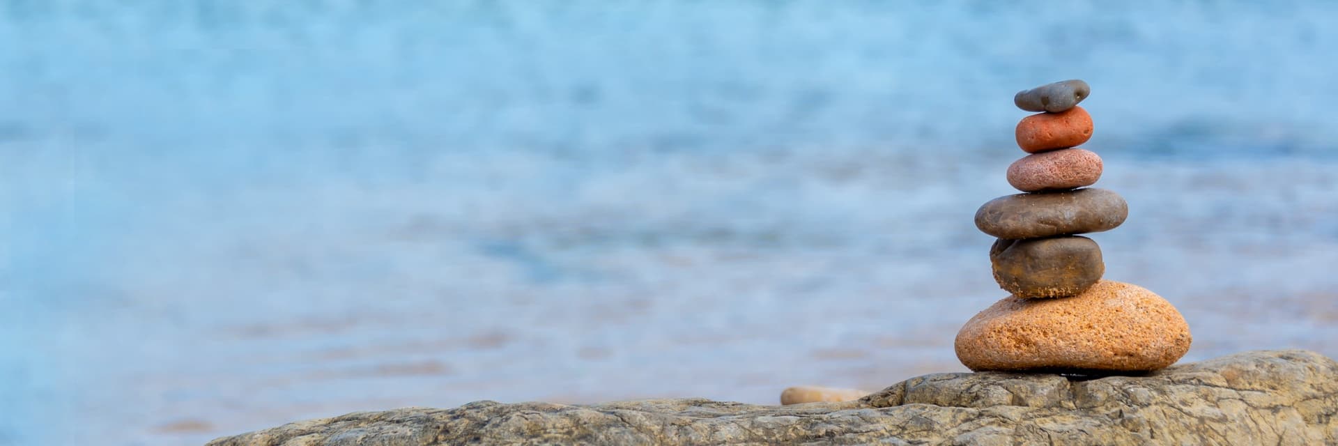 A balanced stack of smooth stones on a rock beside the water