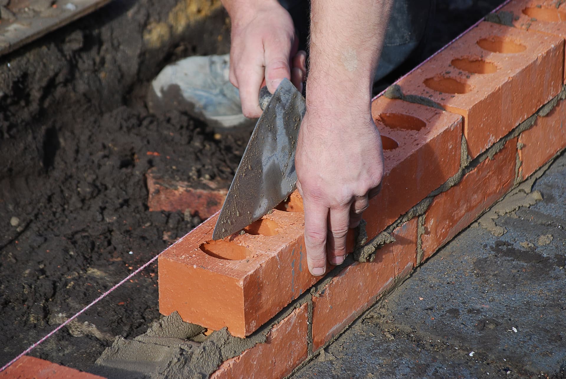 A bricklayer carefully placing a brick on a wall