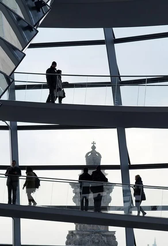 Silhouettes of people walking along a curved ramp inside a modern glass dome