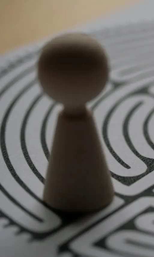 A wooden game piece standing at the entrance of a circular labyrinth