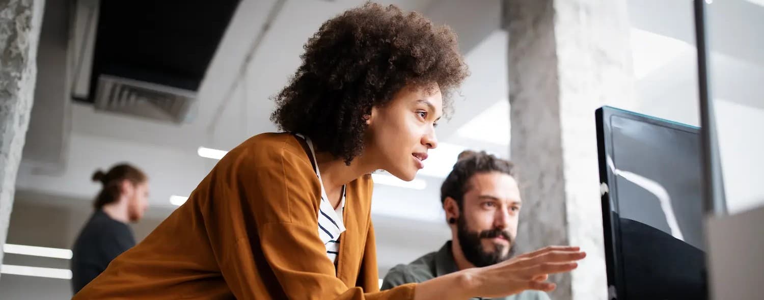 Two colleagues reviewing work together at a computer